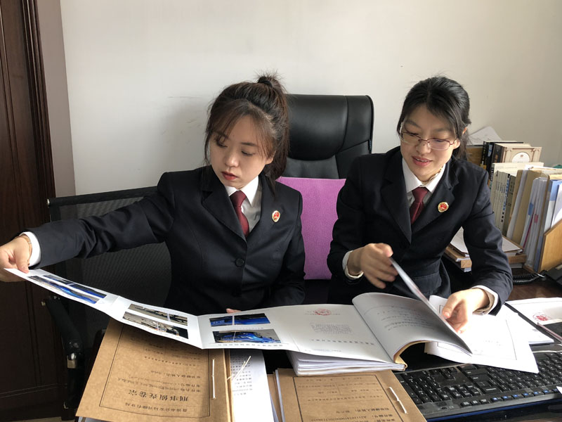 图一：陈月（右一）告诉记者（左一）如何审查、分析案卷。