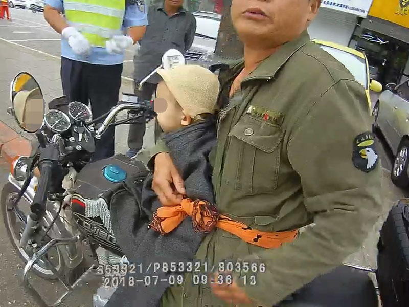 骑摩托车男子仅用一根布条将小男孩固定在自己身上，行驶在马路上 (2)