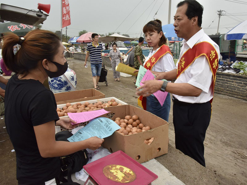 1锦州市委政法委政治部主任、市扫黑办宣传组组长李伟(右一)走进集市进行普法宣传