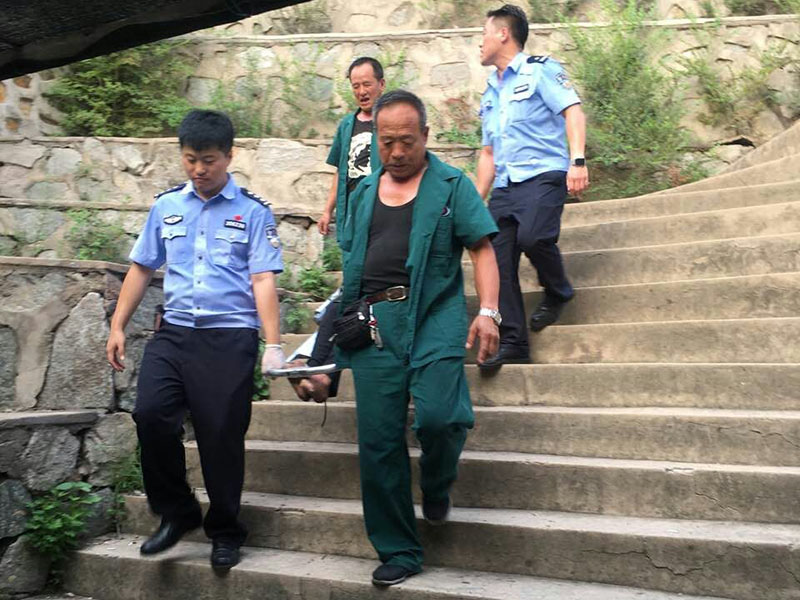 民警和急救人员将中暑男子抬上急救车