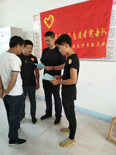 齐刚(右二)正带领着村青年志愿者突击队一起研究改善村容村貌的措施