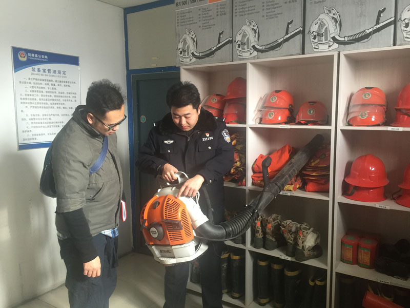 民警王雍贺向记者（左）讲解新进的轻便型德国进口风力灭火器的使用
