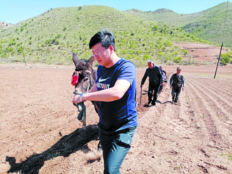 魏铁夫（前）与村民在“扶贫种植园”里耕种