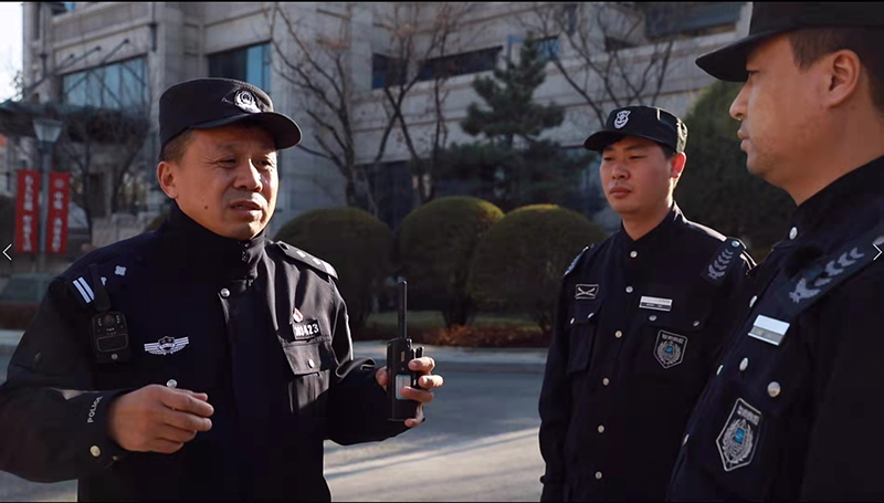 李华瑞（左一）在向小区保安介绍当前的治安情况