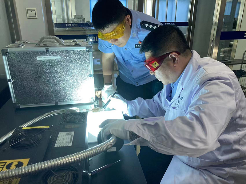 丁友（左）与同事在实验室对现场提取的指纹进行反复比对