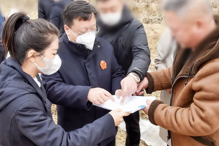 新民市法院大民屯法庭庭长王旌棘（左二）与委托代理人、村委会干部核对土地面积——马震宇摄