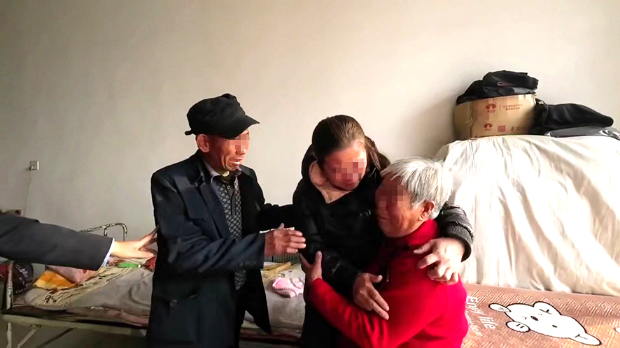 “肚兜女婴”王丽（中）与父母团圆。