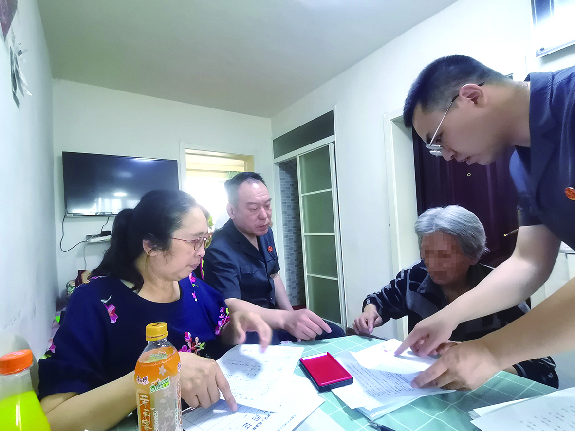 付承志（右一）胡善福（左二）指导潘某荣（右二）在调解书上签字、按手印