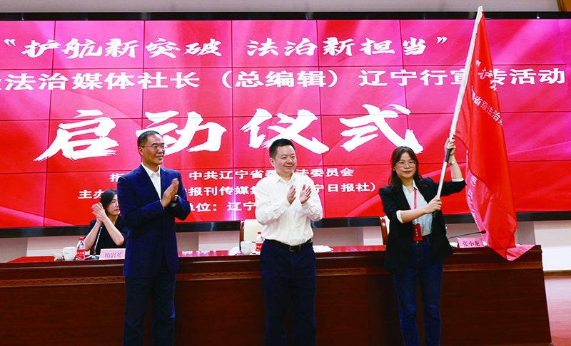 辽宁报刊传媒集团（辽宁日报社）党委副书记、总编辑张小龙（右二），辽宁省委政法委副书记米德龙（右三）向采访团代表授旗