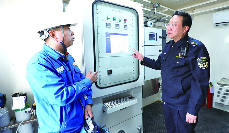 郭国军（右）检查污水处理厂废气处理工艺运行情况