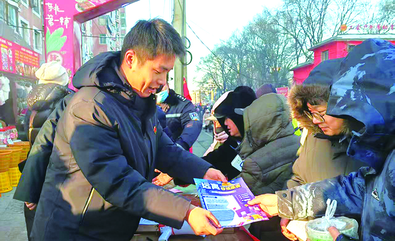 工作人员在早市上讲解反诈常识