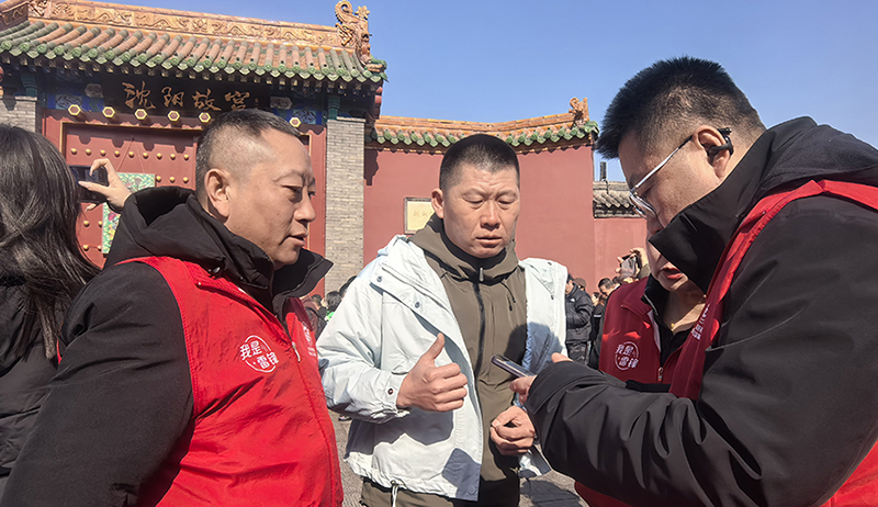 高聪(左)和志愿者正在帮助游客订票