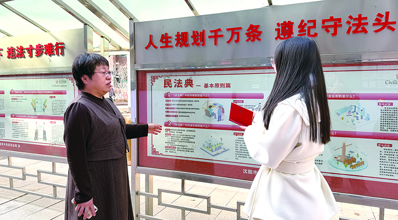 头题图，王丽娟（左）向记者介绍社区构建的“一广场、一长廊、一终端”立体普法阵地情况。