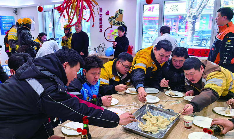年三十的城市温暖补给站里，外卖小哥们正吃着热乎乎的饺子。