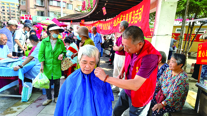 头题图，在每月28日开展的“邻里守望 情暖社区”学雷锋便民志愿服务活动中，党员志愿者为辖区老人义务理发。