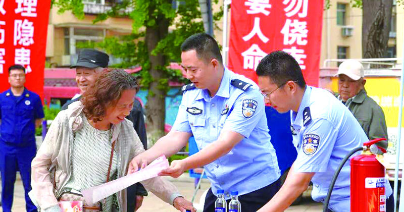 民警向市民发放消防科普手册。  刘文琳 摄