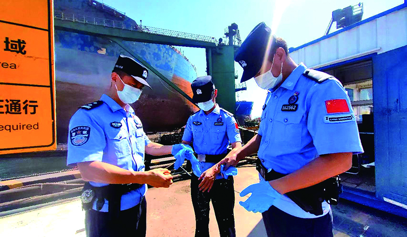 高温酷暑下，民警穿戴防护装备，做好登轮查验前准备工作。