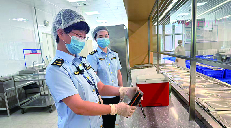 执法人员使用检测仪对餐具消毒效果进行快速检测。 本报记者 张乐悦 摄