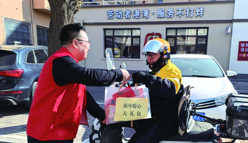 在阜新首家新就业群体服务中心门口，志愿者为外卖小哥送上新年暖心大礼包（受访单位供图） 拷贝